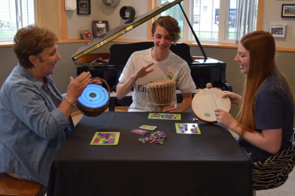 Sally and Teenage Students Playing Rhythms in Rhythm Riot on Drums